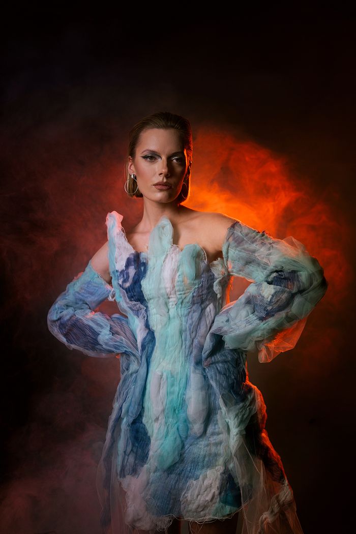 our-story-01 Striking portrait of a woman in a unique avant-garde dress with dramatic lighting.