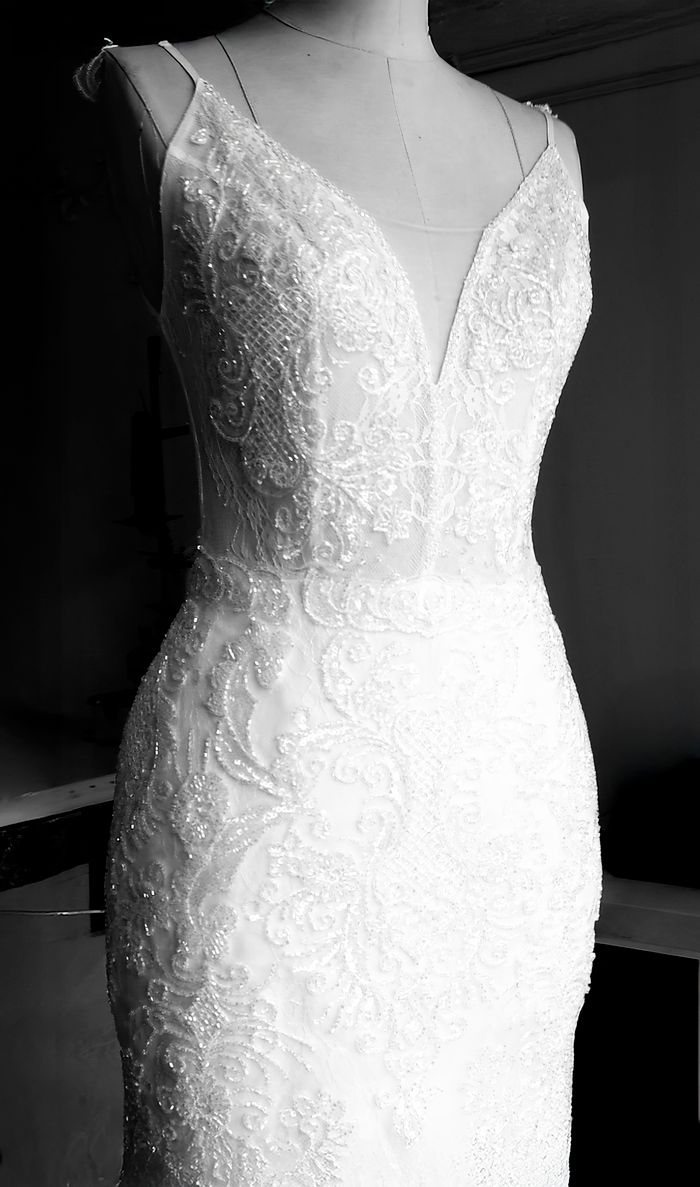 Close-up of an elegant lace wedding dress displayed on a mannequin.