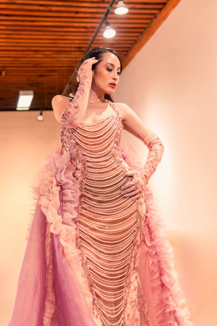 The Art of Drawing Readers In: Your attractive post title goes here A glamorous woman poses in a pink couture gown under indoor lighting.