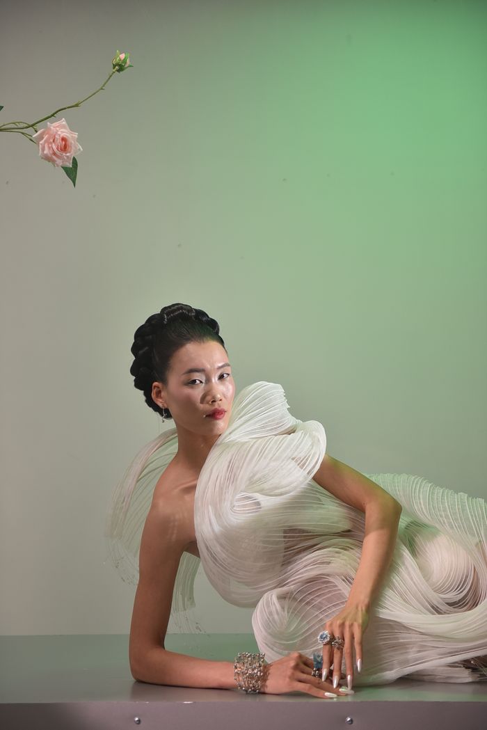 A stylish portrait of a model in an elaborate dress with floral accents, highlighting contemporary fashion.