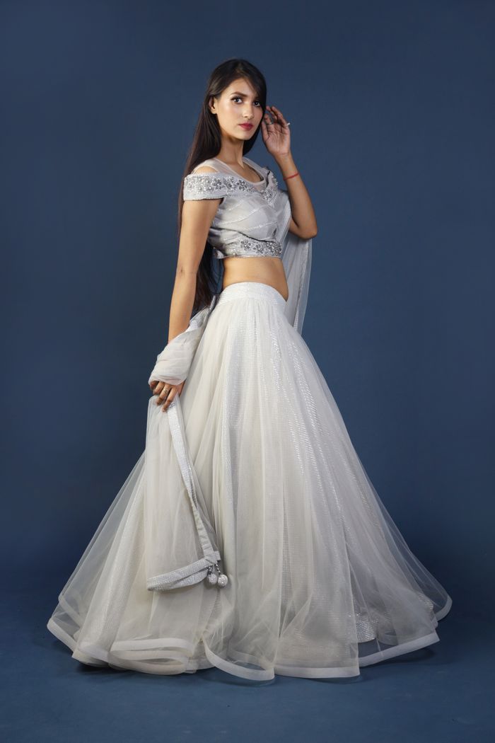 A stylish and graceful woman in a traditional white saree and elegant pose, showcasing cultural attire.